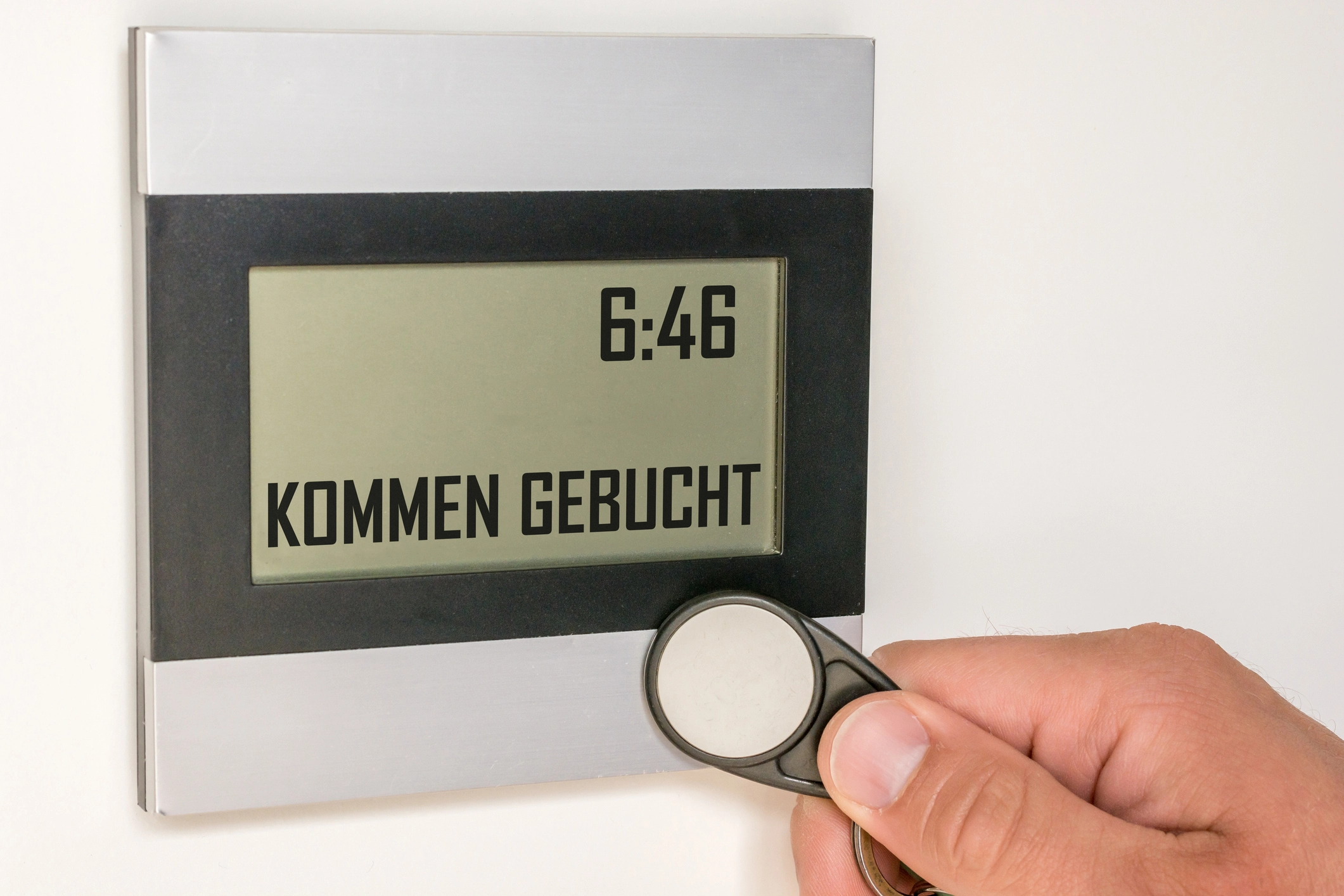 Elektronisches Zeiterfassungsgerät zeigt „6:46 – Kommen gebucht“, Hand hält Transponder zum Einchecken.